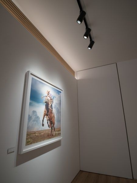 Spotlights belyser ett inramat konstverk i ett galleriutrymme