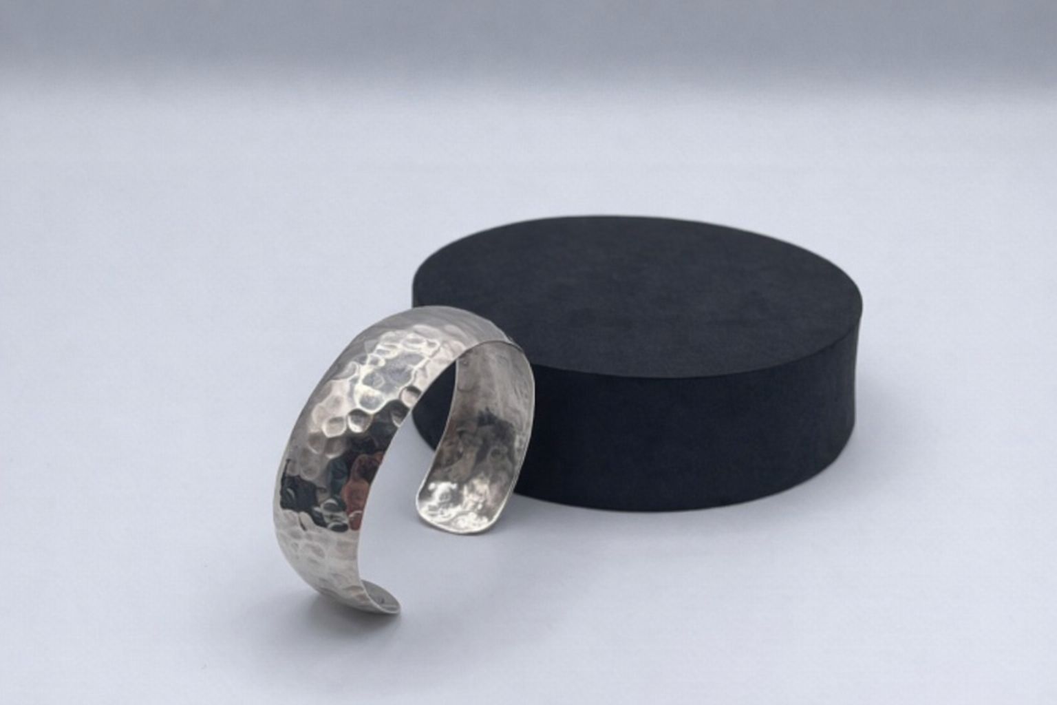 Slaghamrad silvermanschett mot svart bakgrund, visar hantverk.